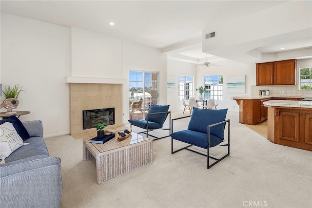 living area with light colored carpet, recessed lighting, a tile fireplace, baseboards, and ceiling fan