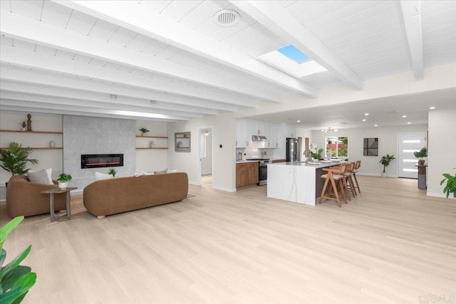 4566 Derrick Dr, San Diego, CA 92117 - living area with beamed ceiling, light wood-type flooring, baseboards, and a large fireplace