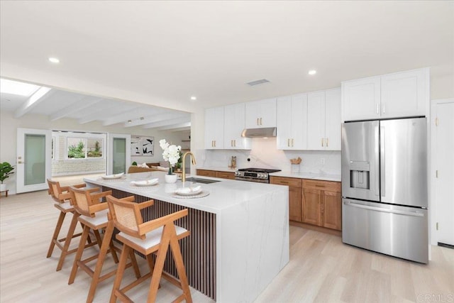 4566 Derrick Dr, San Diego, CA 92117 - kitchen with appliances with stainless steel finishes, a sink, under cabinet range hood, light wood-type flooring, and beamed ceiling