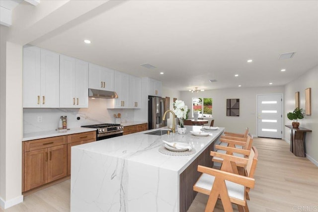 4566 Derrick Dr, San Diego, CA 92117 - kitchen featuring under cabinet range hood, stainless steel appliances, a sink, a large island, and a kitchen bar