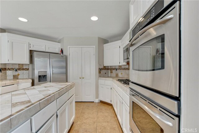 24062 Fuschia Ct, Murrieta, CA 92562 - kitchen featuring appliances with stainless steel finishes, tile countertops, white cabinets, and recessed lighting