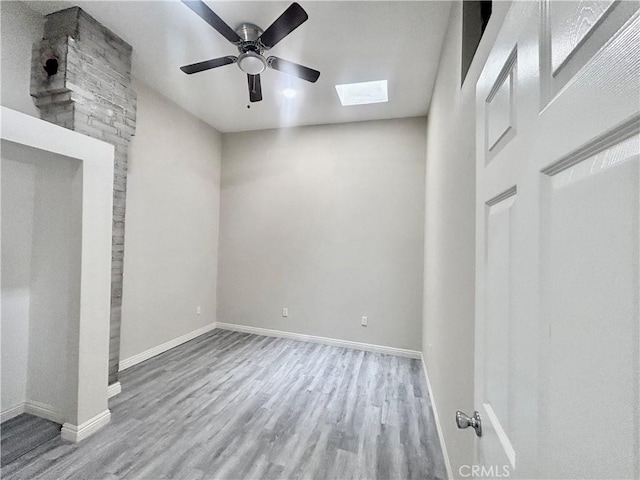 128130 E 1st St, Buttonwillow, CA 93206 - unfurnished bedroom featuring a skylight, wood finished floors, baseboards, and ceiling fan