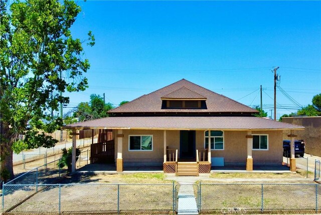 128130 E 1st St, Buttonwillow, CA 93206 - view of front of house with covered porch, a gate, a fenced front yard, and stucco siding