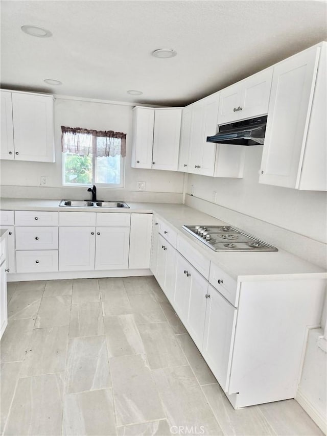 128130 E 1st St, Buttonwillow, CA 93206 - kitchen with a sink, under cabinet range hood, stainless steel electric stovetop, white cabinetry, and light countertops