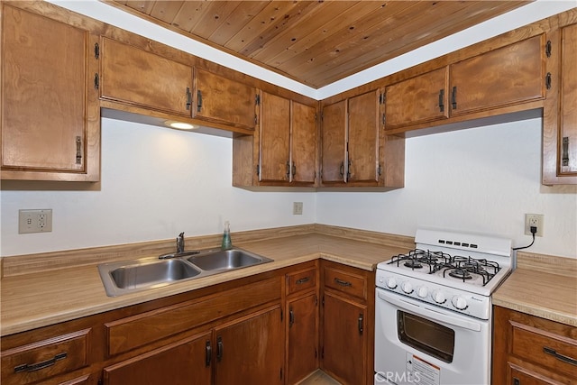 kitchen featuring white gas stove, a sink, light countertops, wood ceiling, and brown cabinets