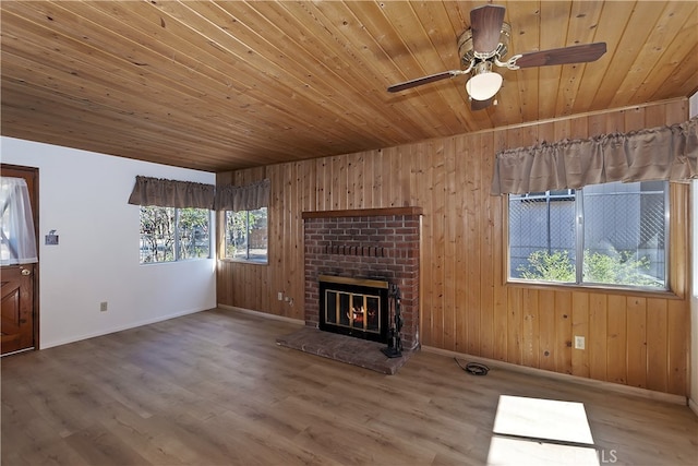 unfurnished living room featuring wood ceiling, healthy amount of natural light, baseboards, and wooden walls