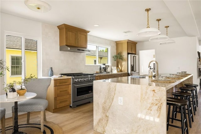 1909 Montair Ave, Long Beach, CA 90815 - kitchen with premium appliances, under cabinet range hood, a breakfast bar area, light wood-type flooring, and brown cabinets