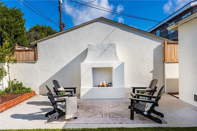 1909 Montair Ave, Long Beach, CA 90815 - rear view of property featuring a warm lit fireplace, a patio, stucco siding, and fence