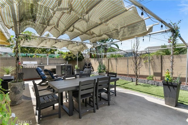 view of patio featuring outdoor dining space, a fenced backyard, exterior kitchen, and area for grilling