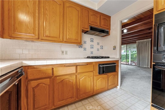 926 E Dalton Ave, Glendora, CA 91741 - kitchen with under cabinet range hood, tile countertops, black appliances, a warming drawer, and decorative backsplash