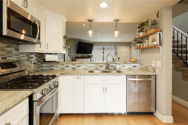 290 Victoria St Unit 19, Costa Mesa, CA 92627 - kitchen with appliances with stainless steel finishes, a sink, tasteful backsplash, white cabinets, and a peninsula