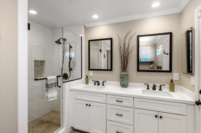 bathroom featuring a tile shower, crown molding, double vanity, and recessed lighting