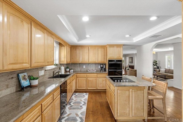 kitchen with light brown cabinets, a sink, black appliances, wood finished floors, and light stone counters