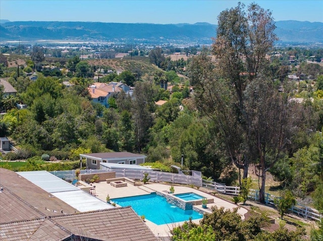 view of pool with a mountain view, a pool with connected hot tub, fence, and a patio area