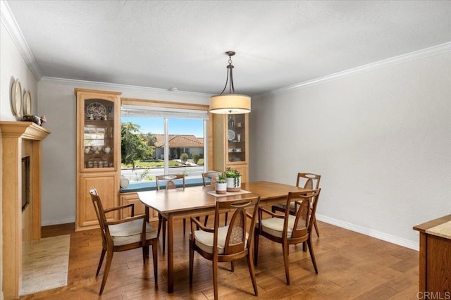 dining room featuring wood finished floors, baseboards, and ornamental molding