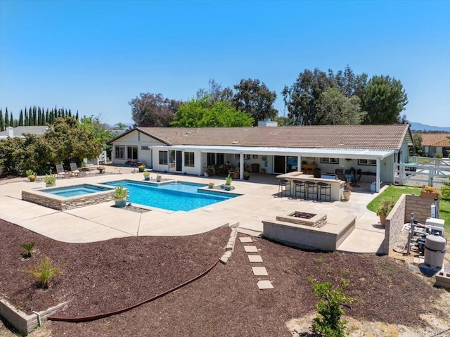 view of pool featuring a patio, fence, a fire pit, and a pool with connected hot tub