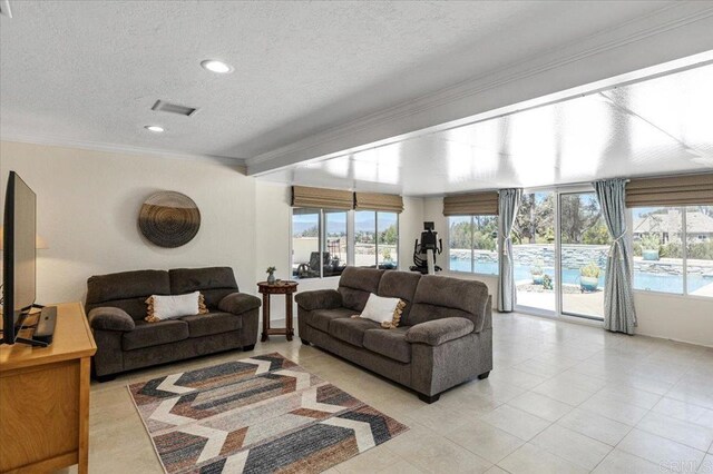 living area featuring a textured ceiling, healthy amount of natural light, crown molding, light tile patterned floors, and recessed lighting