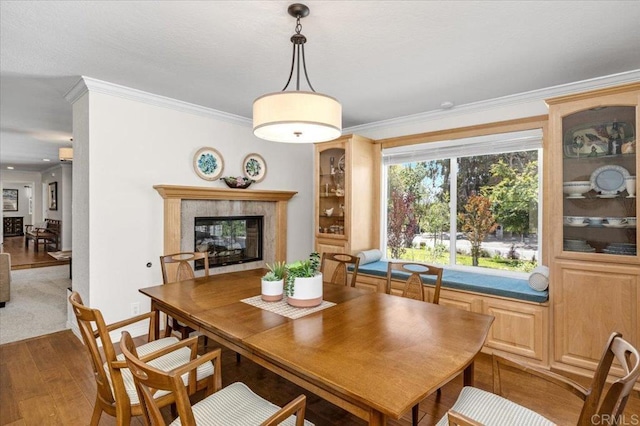 dining space with wood finished floors, ornamental molding, a premium fireplace, and baseboards