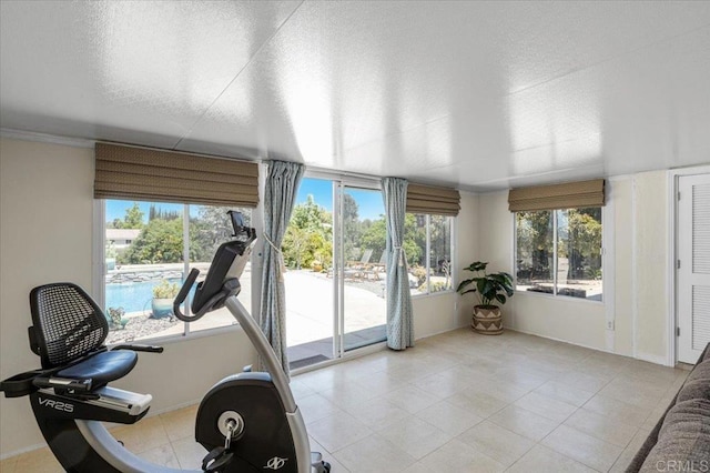 exercise room featuring healthy amount of natural light, a textured ceiling, baseboards, and light tile patterned flooring