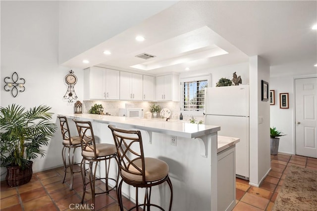 77178 Pauma Valley Way, Palm Desert, CA 92211 - kitchen featuring white appliances, a peninsula, a kitchen bar, light countertops, and backsplash