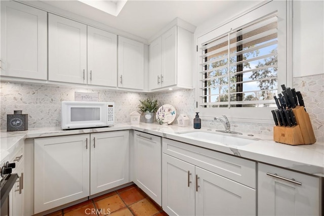 77178 Pauma Valley Way, Palm Desert, CA 92211 - kitchen featuring a sink, white microwave, backsplash, white cabinets, and light stone countertops
