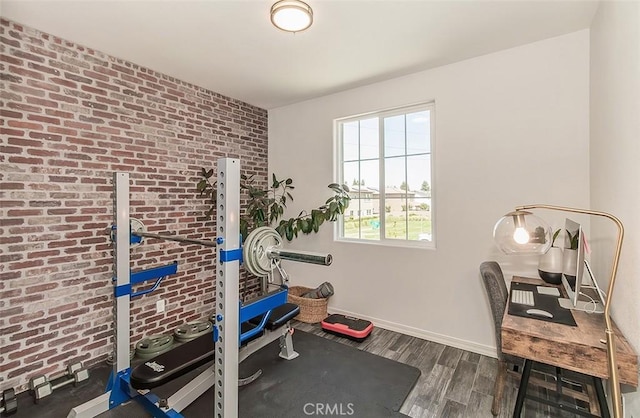 7005 N Astoria Dr, Fresno, CA 93722 - workout area featuring wood finished floors, brick wall, and baseboards
