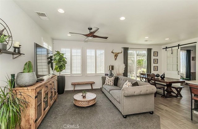 7005 N Astoria Dr, Fresno, CA 93722 - living room featuring a barn door, ceiling fan, recessed lighting, and wood finished floors