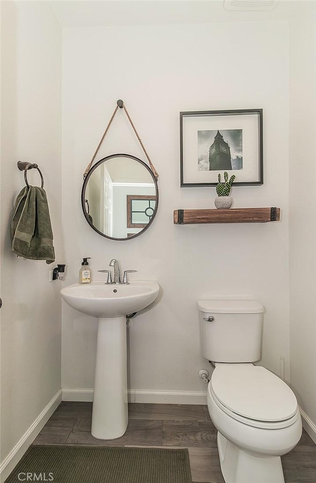 7005 N Astoria Dr, Fresno, CA 93722 - bathroom featuring baseboards, toilet, wood finished floors, and a sink