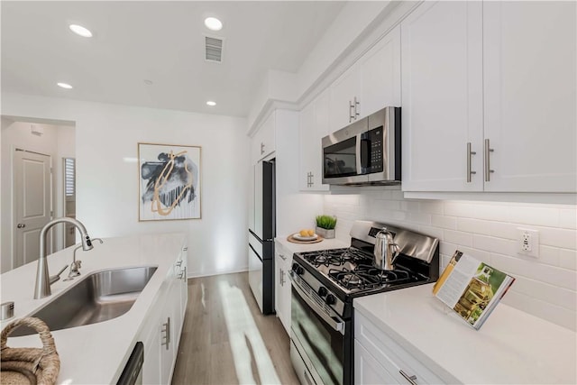 16436 Whittier Blvd Unit 1, Whittier, CA 90603 - kitchen featuring appliances with stainless steel finishes, a sink, light wood-style flooring, white cabinetry, and tasteful backsplash
