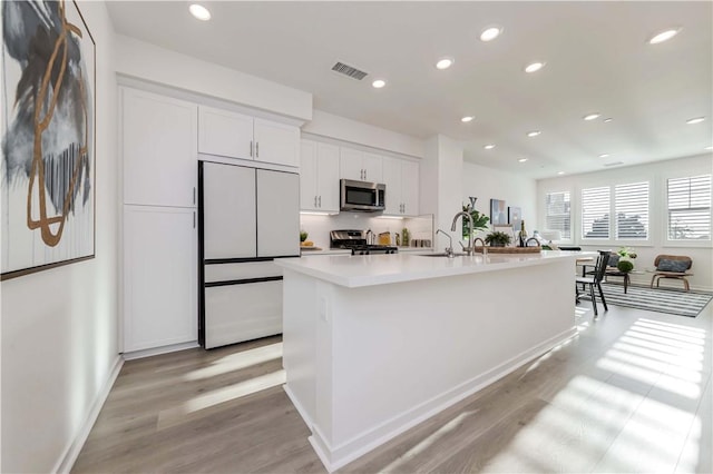 16436 Whittier Blvd Unit 1, Whittier, CA 90603 - kitchen with stainless steel microwave, stove, white built in fridge, white cabinetry, and light wood finished floors