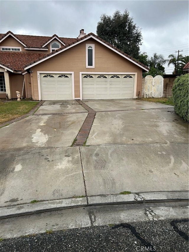 991 Latham St, Colton, CA 92324 - view of front of house with a tile roof, concrete driveway, a garage, a gate, and a chimney