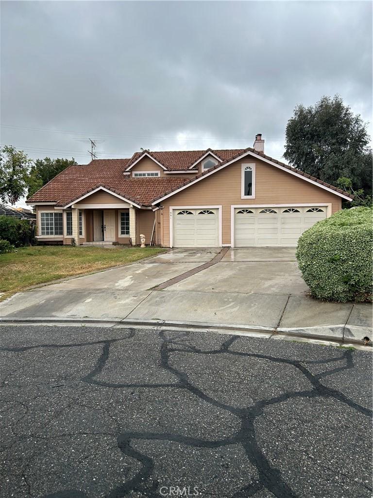 991 Latham St, Colton, CA 92324 - view of front of property with an attached garage, a tiled roof, driveway, a front lawn, and a chimney