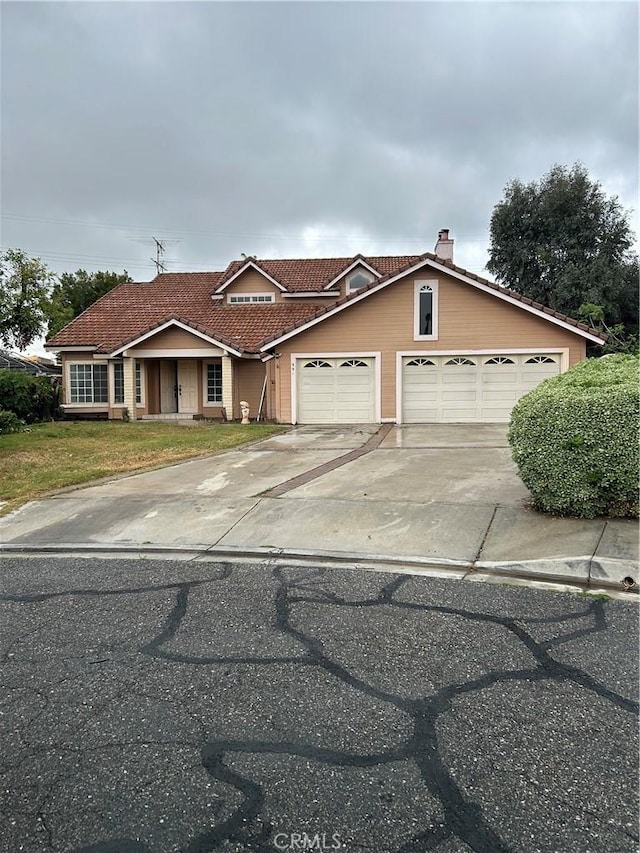 991 Latham St, Colton, CA 92324 - view of front of property with an attached garage, a tiled roof, driveway, a front lawn, and a chimney