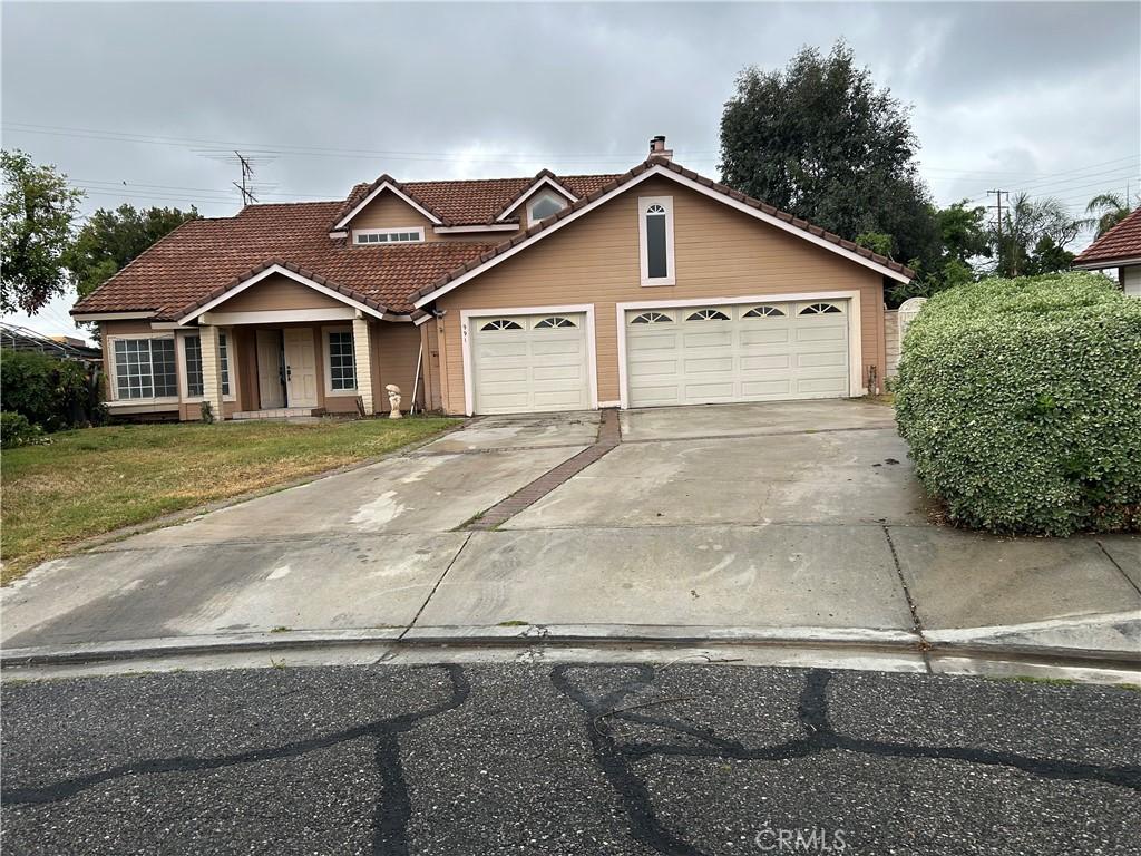 991 Latham St, Colton, CA 92324 - traditional-style house featuring a tiled roof, an attached garage, driveway, and a front lawn