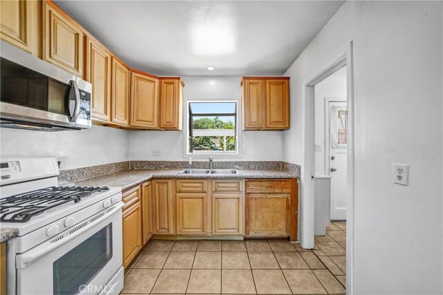 6225 Langdon Ave, Van Nuys, CA 91411 - kitchen with white gas range, stainless steel microwave, a sink, and light tile patterned floors