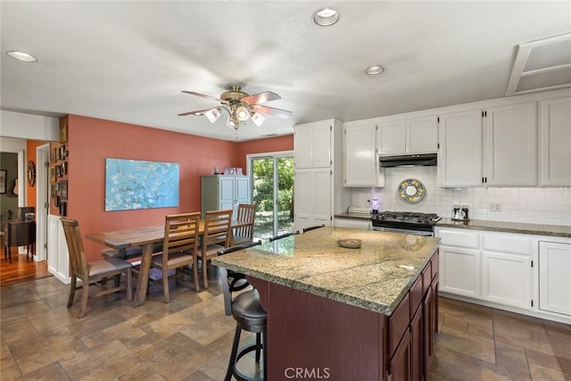 3123 Michael Way, Chico, CA 95973 - kitchen with stainless steel gas range, a center island, backsplash, ceiling fan, and under cabinet range hood