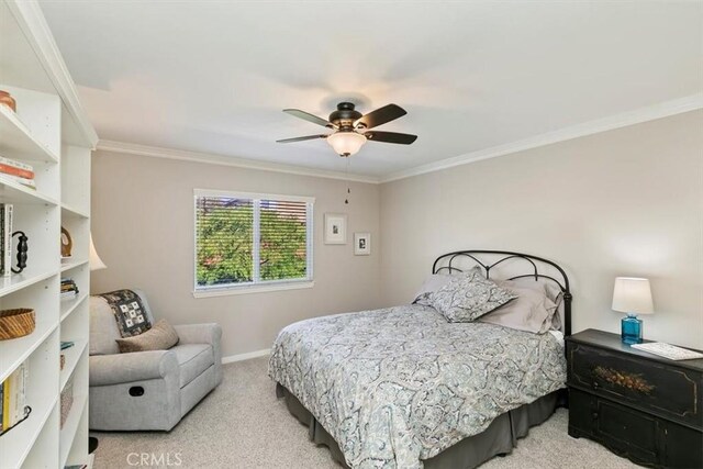 carpeted bedroom featuring ornamental molding, baseboards, and ceiling fan