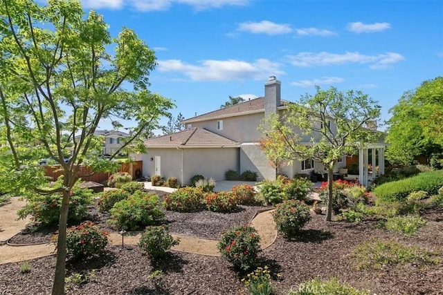 view of side of property with stucco siding, fence, and a chimney