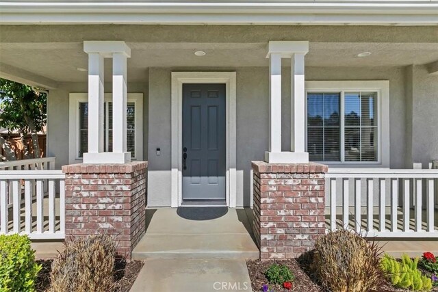 property entrance with a porch and stucco siding