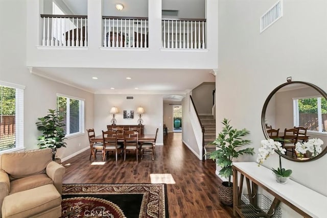 living area with a high ceiling, stairway, wood finished floors, baseboards, and recessed lighting