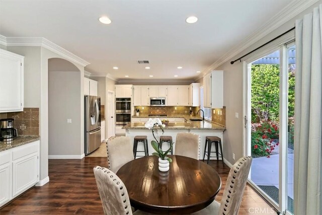 dining room featuring dark wood-style flooring, baseboards, crown molding, and recessed lighting