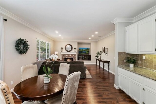 dining area with dark wood finished floors, baseboards, recessed lighting, ornamental molding, and a brick fireplace