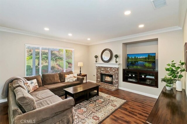 living room featuring crown molding, dark wood-style floors, baseboards, a brick fireplace, and recessed lighting