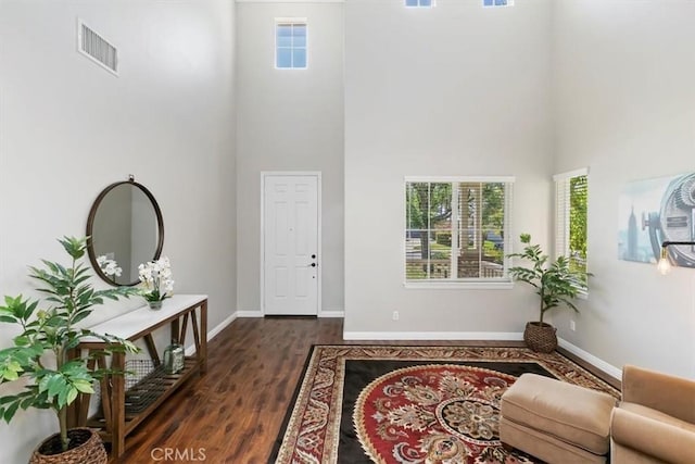 entrance foyer with a high ceiling, dark wood-type flooring, and baseboards