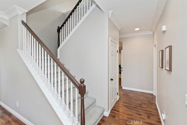 stairs with wood finished floors, ornamental molding, and baseboards