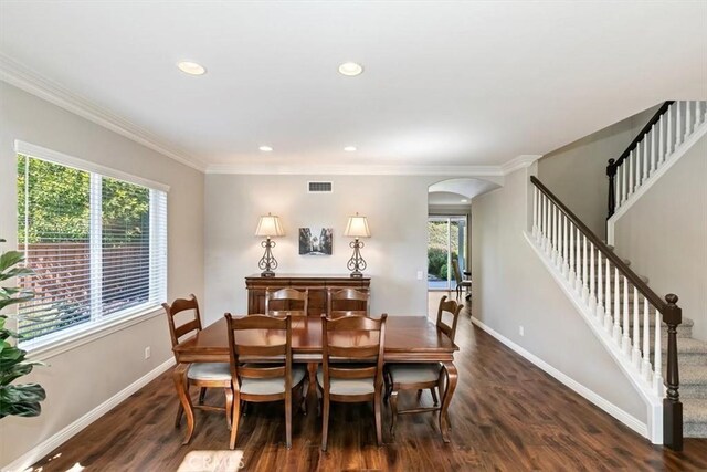 dining space featuring arched walkways, baseboards, wood finished floors, stairs, and crown molding