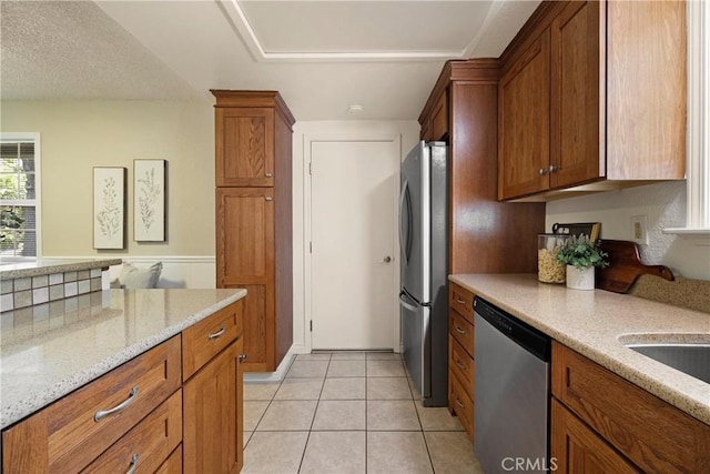20 Parkhurst St, Chico, CA 95928 - kitchen featuring appliances with stainless steel finishes, brown cabinetry, light stone counters, and light tile patterned floors