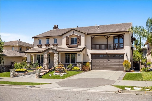 traditional-style home featuring stucco siding, driveway, a balcony, and an attached garage
