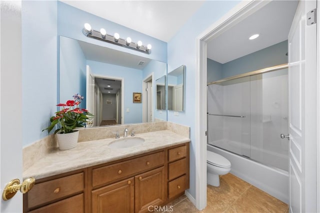 bathroom featuring toilet, vanity, tile patterned floors, and bath / shower combo with glass door