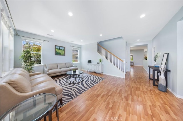 living area with light wood-style flooring, stairway, baseboards, and recessed lighting